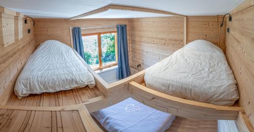 two beds in a wooden room with a window at Chalet école des cimes in Bozel