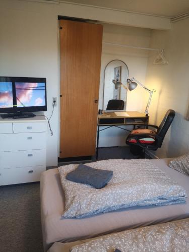 a bedroom with a bed and a desk and a television at 2 værelser m minikøkken brusekabine og toilet 4 prs in Kolding