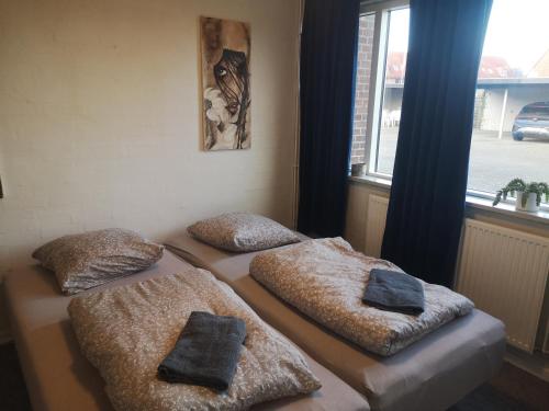 two twin beds in a room with a window at 2 værelser m minikøkken brusekabine og toilet 4 prs in Kolding
