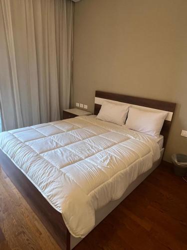 a large bed with white sheets and pillows in a bedroom at Balcony studio in Sheikh Zayed