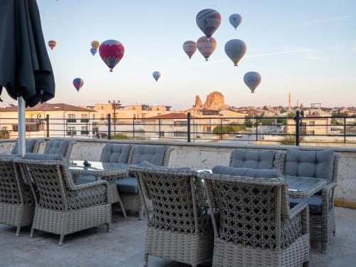 a patio with tables and chairs and hot air balloons at Cappadocia ByHan Hotel - Special Class in Uçhisar