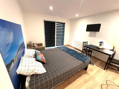une chambre avec un lit, un bureau et une télévision dans l'établissement Refuge des voyageurs Studio neuf - Horizon indépendant rez de jardin, à Plouédern