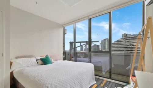 una camera da letto con un letto bianco e una grande finestra di Central Melbourne 2BR Balcony Apartment a Melbourne