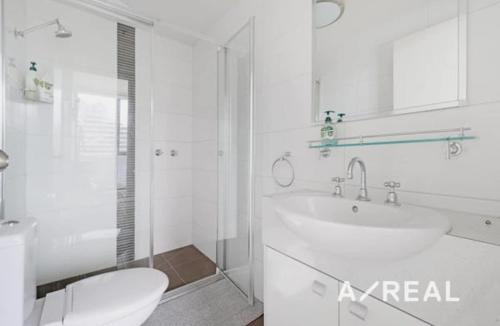 un bagno bianco con lavandino e WC di Central Melbourne 2BR Balcony Apartment a Melbourne