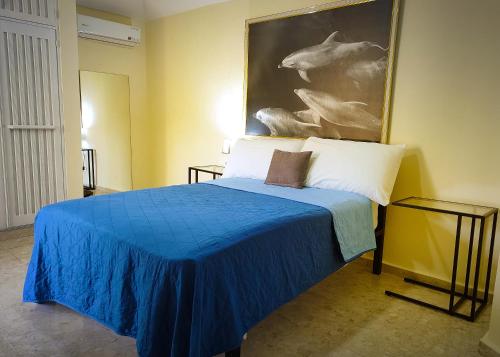 a bedroom with a blue bed with a painting on the wall at Refugio Encantador in Santo Domingo