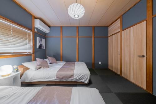 a bedroom with two beds and a blue wall at 蝶 プレイルーム家族で楽しめるお部屋 手作りの和風のお部屋で疲れを癒す 11台のベッド 22名利用 in Osaka