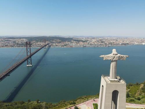 a statue of christ the redeemer in front of a bridge at Stylish Cacilhas rooms near the ferry to central Lisbon in Almada