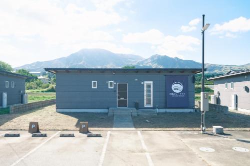a small blue building with mountains in the background at 阿蘇ビューテラス in Aso