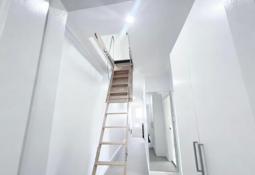 Burwood Family Guest Home في سيدني: سلم يؤدي إلى غرفة ذات جدار أبيض