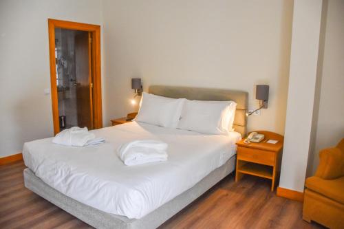 une chambre avec un lit avec deux serviettes dessus dans l'établissement Hotel Toural, à Guimarães