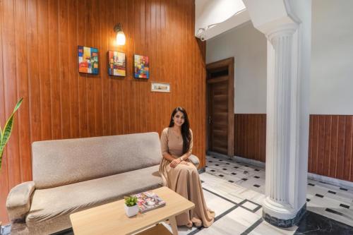 une femme assise sur un canapé dans une pièce dans l'établissement FabHotel Bless Inn, à Allahābād