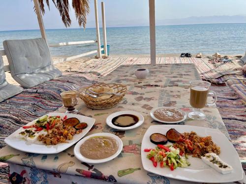 - une table avec deux assiettes de nourriture sur la plage dans l'établissement Sea View Camp Nuweiba, à Wāsiţ