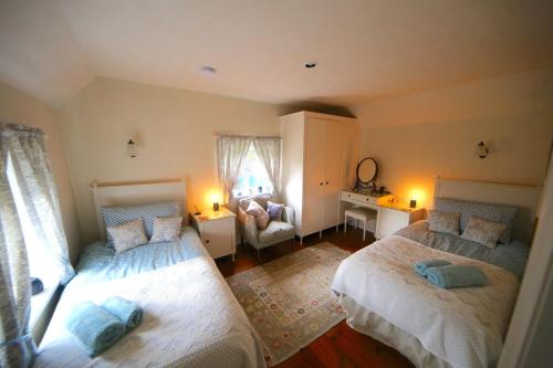 a bedroom with two beds and a chair in it at 3-bedroom cottage set in a large enclosed garden in Thatcham