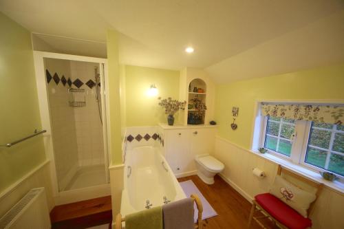 a bathroom with a tub and a shower and a toilet at 3-bedroom cottage set in a large enclosed garden in Thatcham