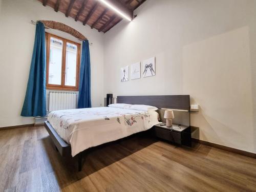a bedroom with a bed with blue curtains and a window at "Suite del Borgo" charming flat at 30 min from Florence, 2 Smart TV in San Giovanni Valdarno
