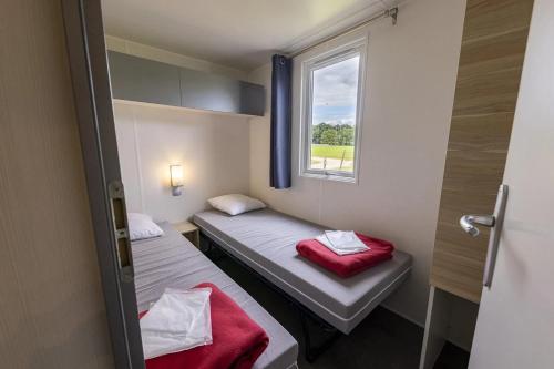 two beds in a small room with a window at Camping 5 étoiles - Parc aquatique - eebfed in Sainte-Catherine-de-Fierbois