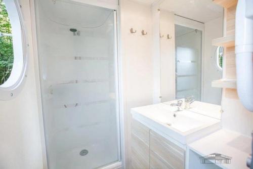 a white bathroom with a shower and a sink at Camping 3 étoiles - Parc aquatique - ccbbaia 
