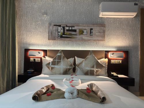 un animal de peluche sentado encima de una cama en FOPROLUX Palace, en Douala