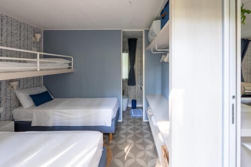 two beds in a small room with blue walls at Vibra Glamping in Cavallino-Treporti