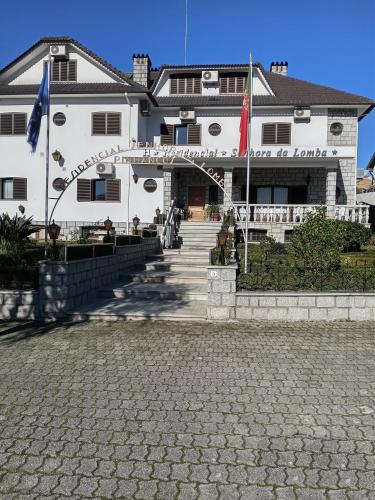 a large white building with a staircase in front of it at Residencial Sra. da Lomba in Pinhanços
