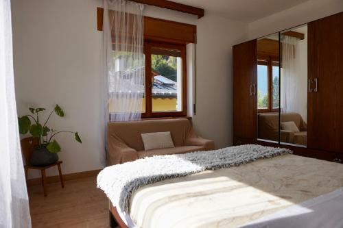 una camera da letto con un letto, un divano e una finestra di Casa vacanze Danoi Dolomiti a Canale dʼAgordo