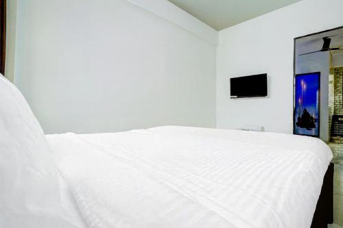 een wit bed in een witte kamer met een tv bij A R Residency in Navi Mumbai