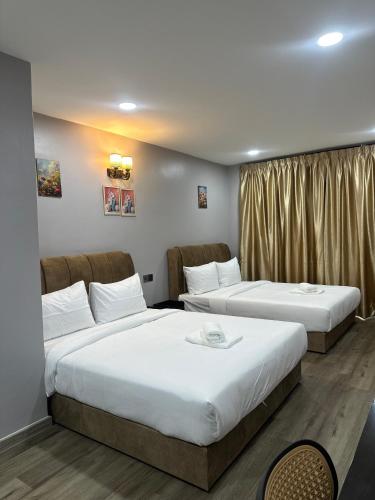 a hotel room with two beds and a window at Lux City Hotel in Seremban