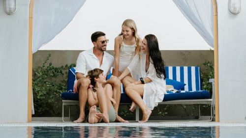 eine Familie neben einem Pool in der Unterkunft JA Ocean View Hotel, Jumeirah Beach Dubai in Dubai