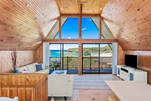 a living room with a couch and a tv at Sea-renity in Kioloa