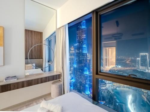 ein Schlafzimmer mit Blick auf die Skyline der Stadt aus einem Fenster in der Unterkunft Ahlan HH - Burj Khalifa and Fountain Views Suite at Grande Downtown in Dubai