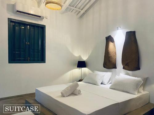 Suitcase في أمبالانغودا: غرفة نوم بيضاء مع سرير مع وسادتين