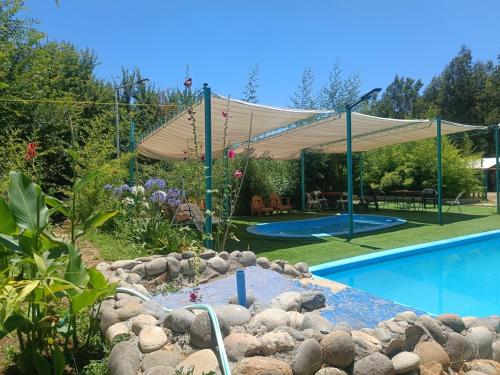una piscina en un jardín con dosel. en Cabañas las Palmeras de Colbun, en Linares