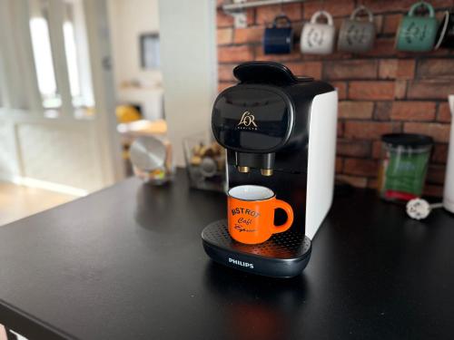 a coffee maker with an orange coffee cup on a counter at Villa de charme avec piscine privée in Ouzouer-sur-Loire