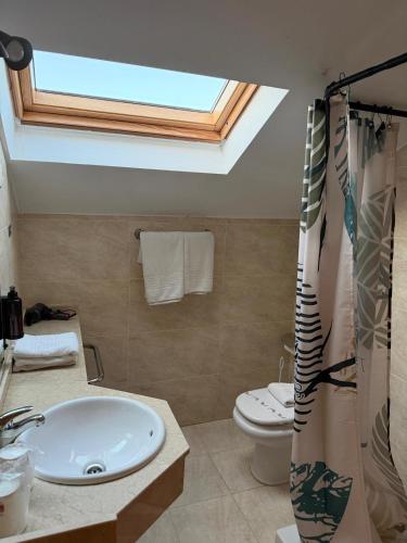 a bathroom with a sink and a toilet with a skylight at Hotel Balcón de San Bartolo in Barreiros