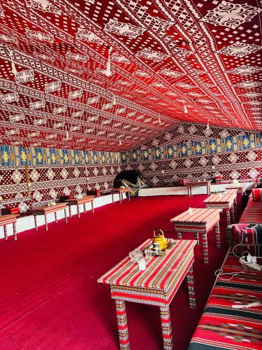 una stanza con tavoli e sedie su un tappeto rosso di Desert Key Camp a Wadi Rum