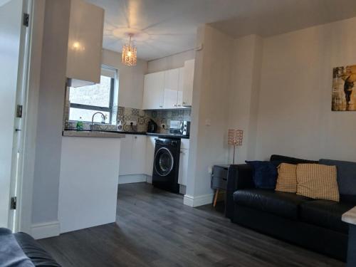 un salon avec un canapé et une cuisine dans l'établissement LARGE 3 BEDROOM HOME, 3 BATHROOMS, FREE PARKING, FAST WIFI, à Belfast