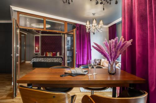 una sala da pranzo con tavolo in legno e tende viola di Grey Champagne Spa by Secret Apartament a Danzica