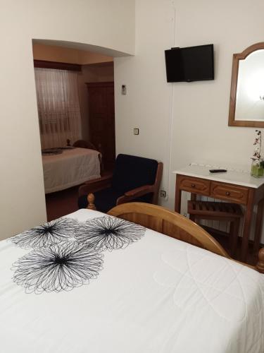 a hotel room with a bed and a desk and a table at Residencial Sra. da Lomba in Pinhanços