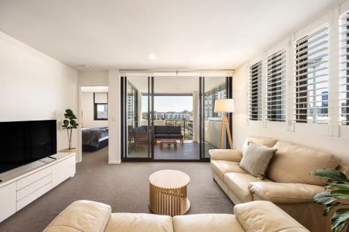 a living room with a couch and a television at Lux1BR Near Stadium, Parking & Balcony in Brisbane