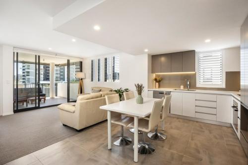 a kitchen and living room with a table and chairs at Lux1BR Near Stadium, Parking & Balcony in Brisbane