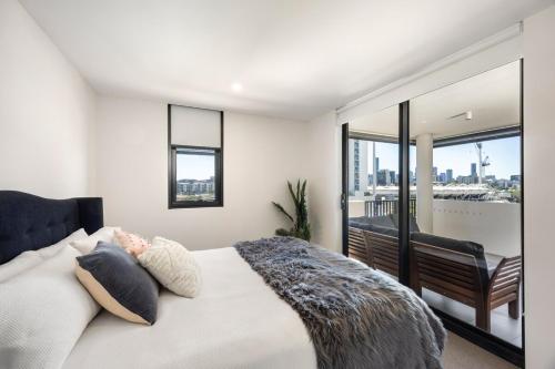 a bedroom with a large bed and a balcony at Lux1BR Near Stadium, Parking & Balcony in Brisbane