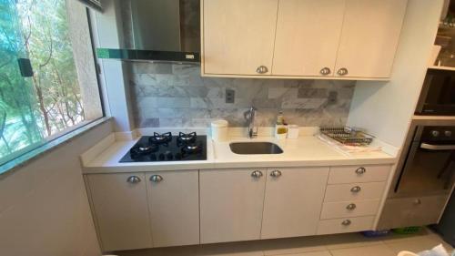 uma cozinha com um lavatório e um fogão em Guarajuba Oliveira em Camassari