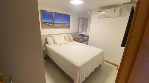 um pequeno quarto com uma cama branca e 2 almofadas em Guarajuba Oliveira em Camassari