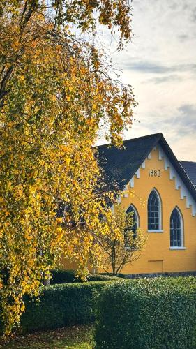 a yellow church with a tree in front of it at Modern vacation Home - Close to sea and nature. in Hejls