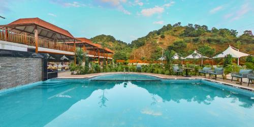 una piscina en un complejo con una montaña en el fondo en KING'SWAY Hotel, en Dūngarpur
