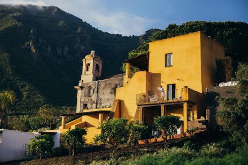 马尔法瑞维斯酒店的山坡上有一栋黄色建筑，带有一个钟楼。