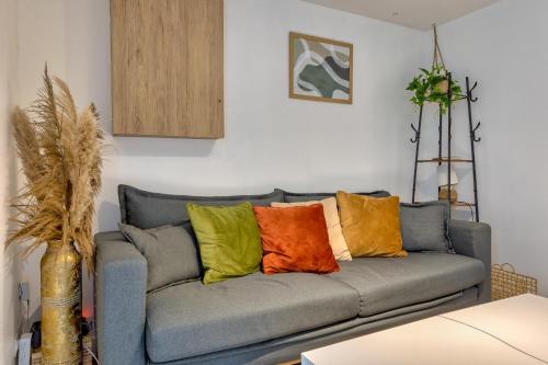 ein Wohnzimmer mit einem Sofa und bunten Kissen in der Unterkunft Le Nid Vouté charmant appartement avec terrasse situé au coeur de Rouen in Rouen