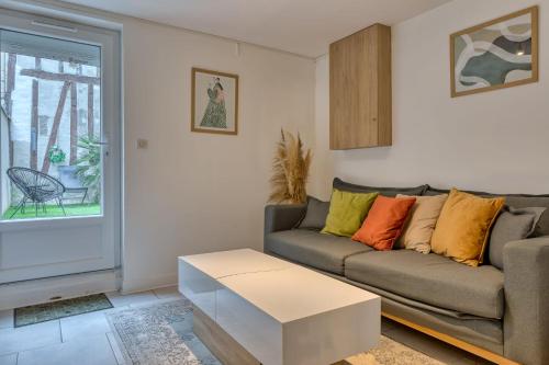 ein Wohnzimmer mit Sofa und Tisch in der Unterkunft Le Nid Vouté charmant appartement avec terrasse situé au coeur de Rouen in Rouen