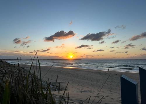 a sunset on a beach with the ocean at Plumeria Cottage Private Coastal Retreat by Australia No 1 Beach in Rock Islet