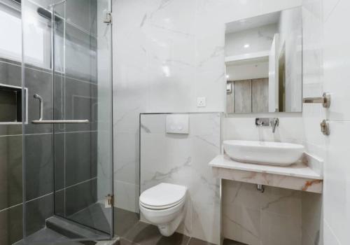 Un baño con inodoro, lavabo y ducha. en The Urbanest, en Lagos